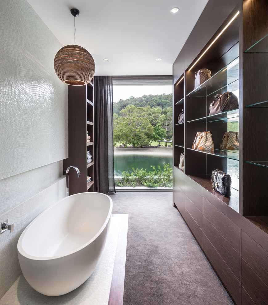 Immagine di una stanza da bagno tropicale di medie dimensioni con ante lisce, vasca freestanding e piastrelle a mosaico