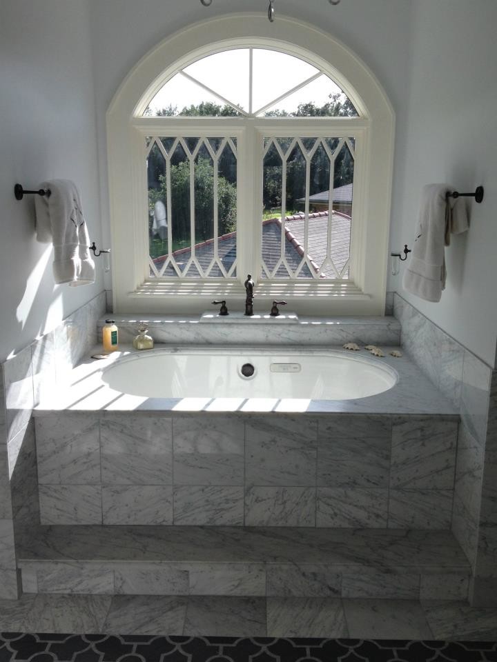 Diseño de cuarto de baño principal romántico con encimera de mármol, bañera encastrada sin remate, baldosas y/o azulejos blancos, baldosas y/o azulejos de piedra y suelo de mármol