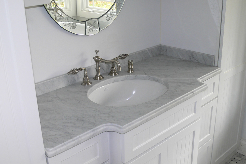 Esempio di una stanza da bagno chic con lavabo sottopiano, ante a filo, ante bianche e top in marmo