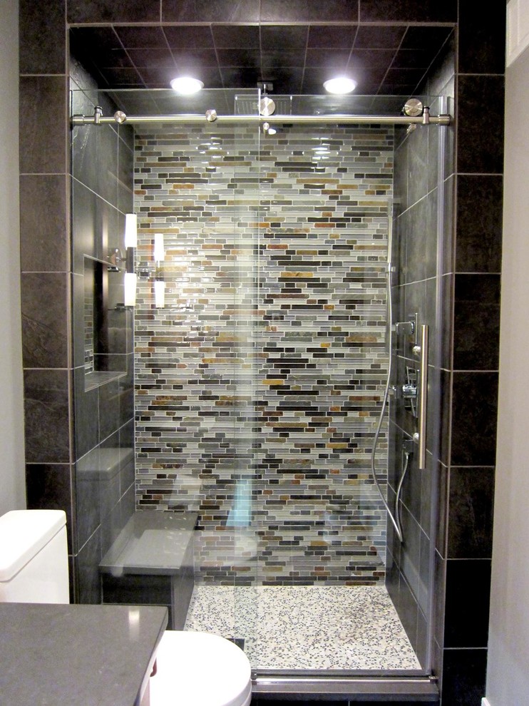 Cette photo montre une salle de bain tendance en bois brun avec un lavabo encastré, un placard à porte plane, un plan de toilette en surface solide, une douche ouverte, un carrelage noir, des carreaux en allumettes et un mur gris.