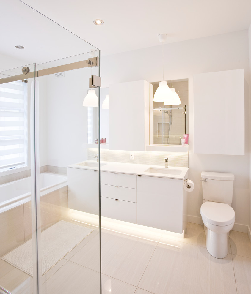 Mid-sized trendy master white tile and slate tile ceramic tile and white floor bathroom photo in Other with flat-panel cabinets, white cabinets, a one-piece toilet, white walls, a drop-in sink, marble countertops and white countertops