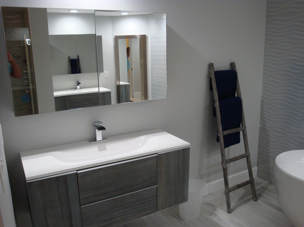 Design ideas for a medium sized contemporary ensuite bathroom in Miami with flat-panel cabinets, grey cabinets, a freestanding bath, blue tiles, porcelain tiles, grey walls, porcelain flooring, an integrated sink, glass worktops, grey floors and white worktops.