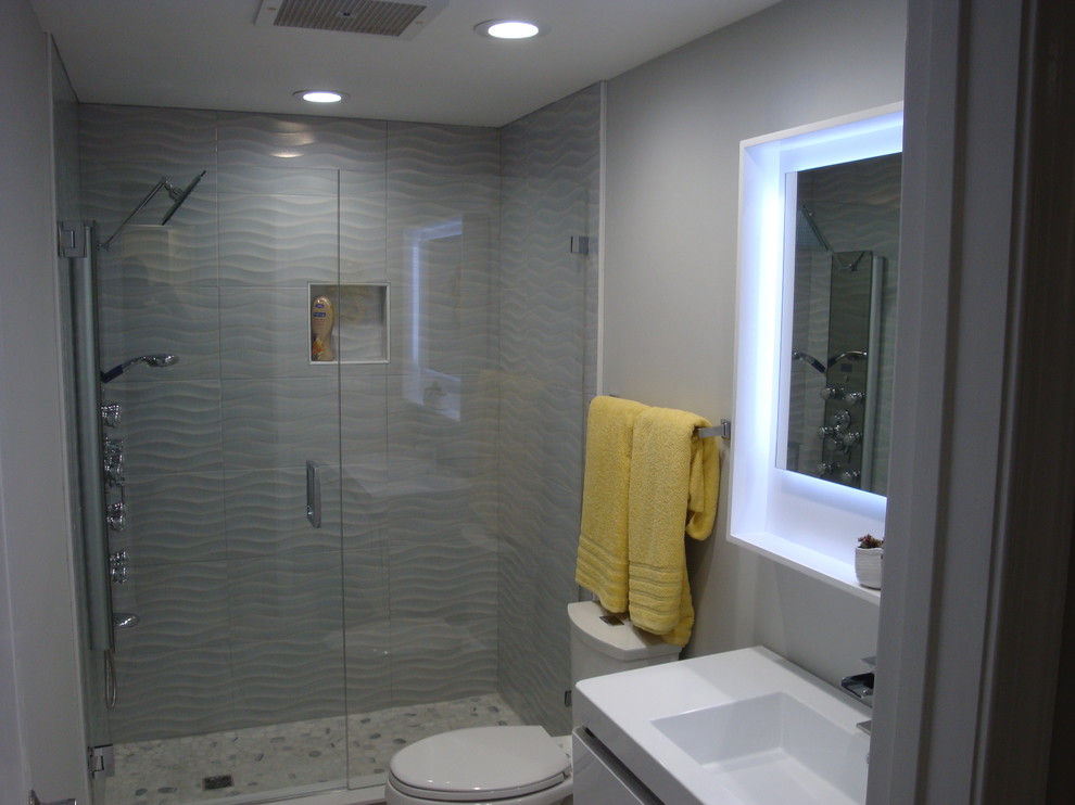 Small trendy 3/4 blue tile and porcelain tile porcelain tile and gray floor bathroom photo in Miami with flat-panel cabinets, white cabinets, gray walls, an integrated sink, solid surface countertops, a hinged shower door and white countertops