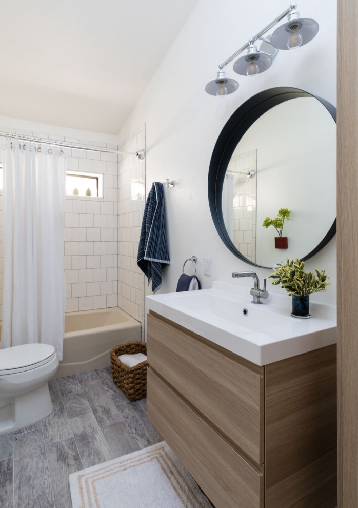 Klassisk inredning av ett mellanstort vit vitt badrum med dusch, med släta luckor, skåp i mellenmörkt trä, ett badkar i en alkov, en dusch/badkar-kombination, en toalettstol med separat cisternkåpa, vit kakel, vita väggar, ett integrerad handfat, grått golv och dusch med duschdraperi