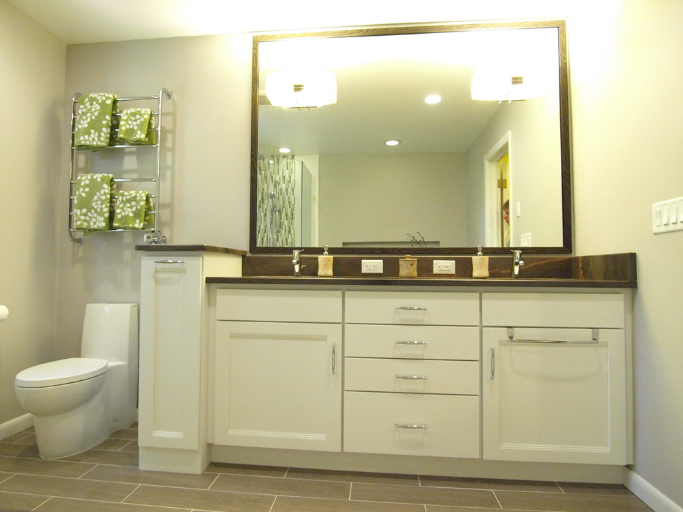 На фото: главная ванная комната среднего размера в стиле неоклассика (современная классика) с фасадами с утопленной филенкой, белыми фасадами, ванной в нише, угловым душем, унитазом-моноблоком, серыми стенами, серым полом, душем с распашными дверями, бежевой плиткой, керамической плиткой, полом из ламината, врезной раковиной и столешницей из гранита с