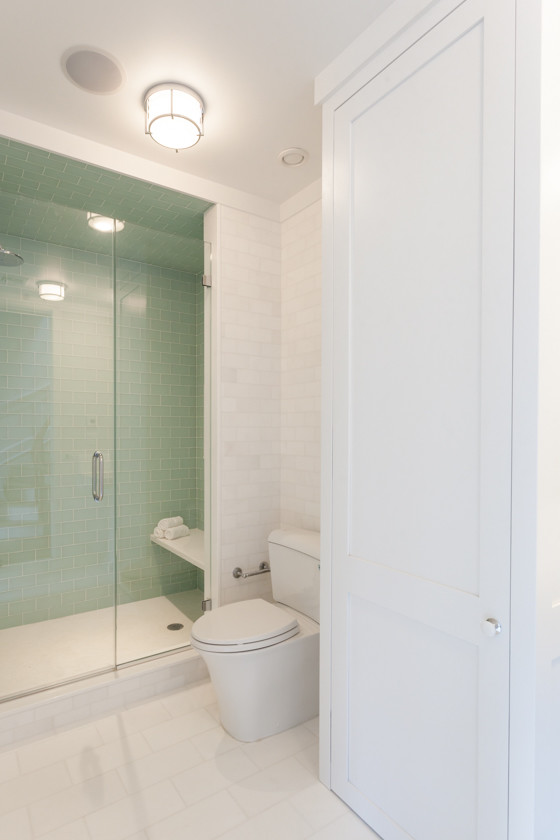 Example of a classic green tile and glass tile marble floor alcove shower design in New York with recessed-panel cabinets, white cabinets, quartz countertops, a two-piece toilet and white walls