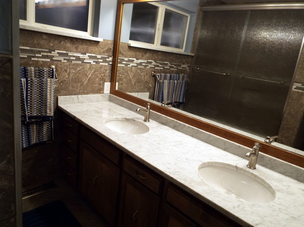 Idee per una stanza da bagno minimal con lavabo sottopiano, ante in stile shaker, ante in legno scuro, top in granito, vasca da incasso, vasca/doccia, WC a due pezzi, piastrelle marroni, piastrelle di vetro, pareti blu e pavimento in gres porcellanato