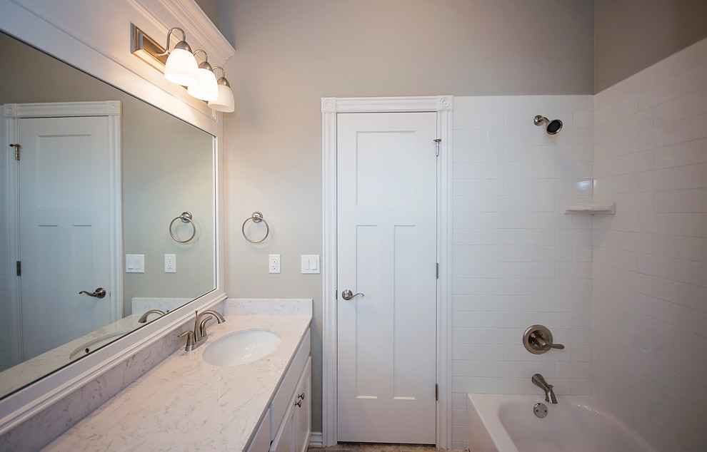 Inredning av ett klassiskt stort badrum, med skåp i shakerstil, vita skåp, ett platsbyggt badkar, en hörndusch, flerfärgad kakel, porslinskakel, grå väggar, klinkergolv i porslin, ett undermonterad handfat och marmorbänkskiva