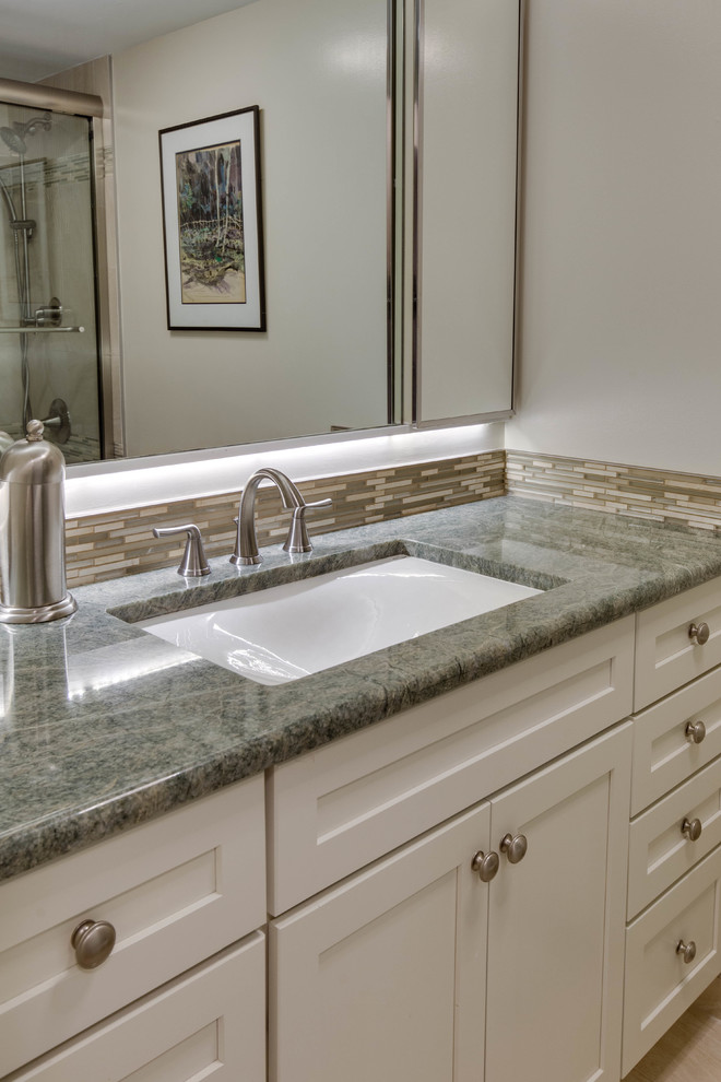 This is an example of a classic bathroom in DC Metro with recessed-panel cabinets, white cabinets, a shower/bath combination, a submerged sink and granite worktops.