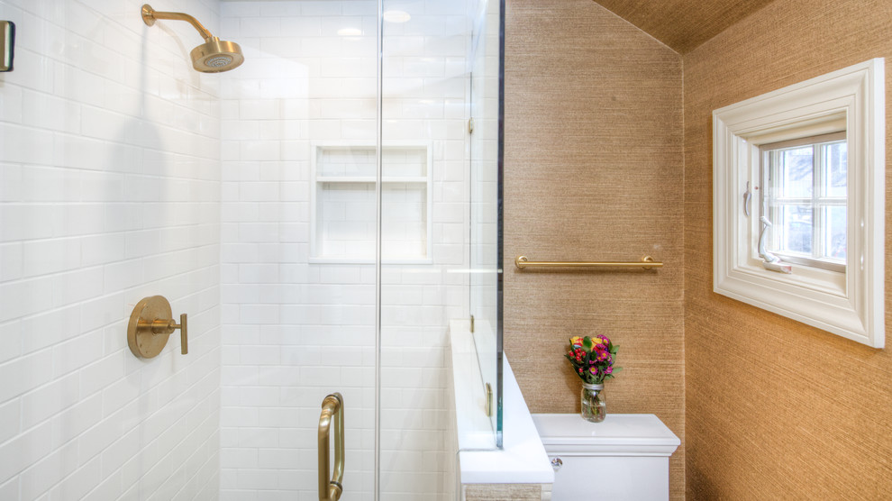 Пример оригинального дизайна: большая ванная комната в современном стиле с фасадами в стиле шейкер, белыми фасадами, угловым душем, раздельным унитазом, белой плиткой, плиткой кабанчик, коричневыми стенами, полом из керамогранита, душевой кабиной, врезной раковиной, мраморной столешницей, бежевым полом, душем с распашными дверями и бежевой столешницей