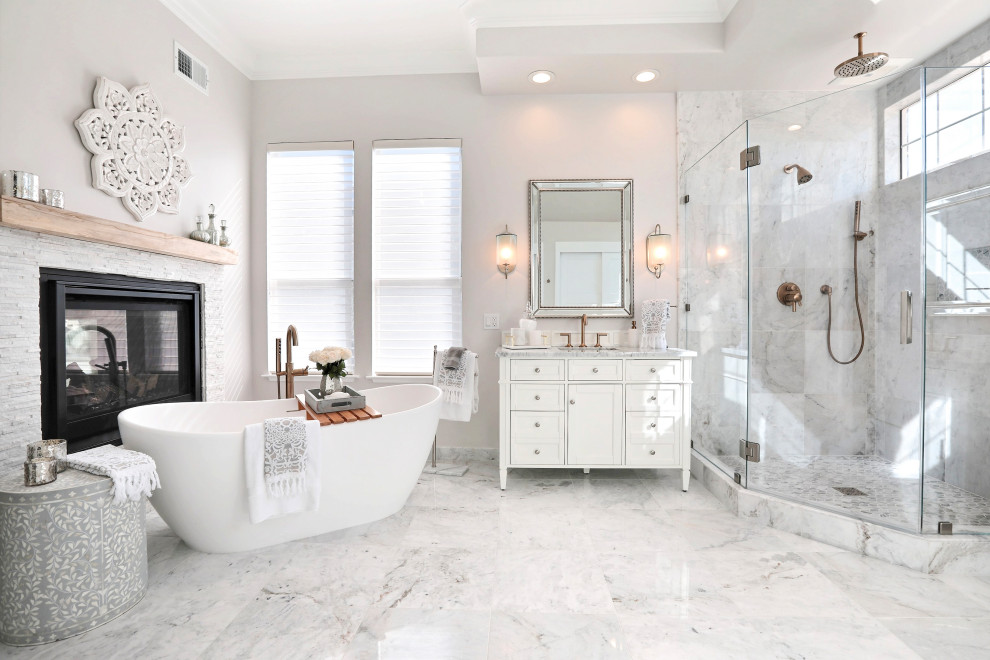 Exemple d'une grande salle de bain principale chic avec un placard à porte shaker, des portes de placard blanches, une baignoire indépendante, une douche d'angle, un carrelage blanc, du carrelage en marbre, un mur blanc, un sol en marbre, un lavabo encastré, un plan de toilette en marbre, un sol blanc, une cabine de douche à porte battante et un plan de toilette gris.