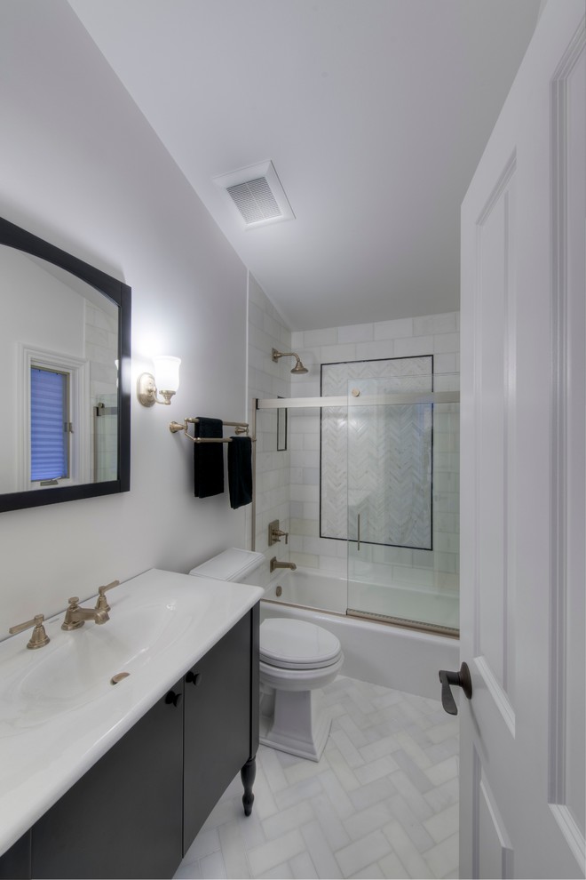 シカゴにあるお手頃価格の中くらいなトラディショナルスタイルのおしゃれなマスターバスルーム (一体型シンク、フラットパネル扉のキャビネット、黒いキャビネット、人工大理石カウンター、アルコーブ型浴槽、シャワー付き浴槽	、一体型トイレ	、白いタイル、石タイル、白い壁、大理石の床) の写真