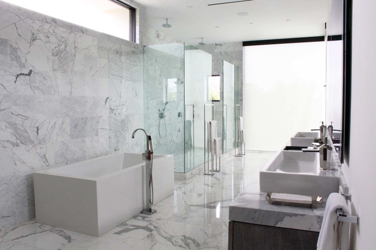 This is an example of a large contemporary ensuite bathroom in Los Angeles with flat-panel cabinets, brown cabinets, a freestanding bath, a corner shower, white tiles, marble tiles, white walls, marble flooring, a trough sink, marble worktops, white floors and a hinged door.