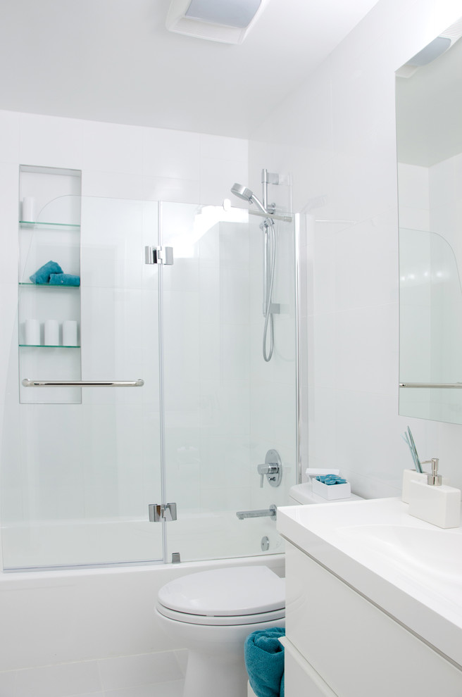 Idee per una stanza da bagno moderna con lavabo da incasso, ante lisce, ante bianche, top in superficie solida, vasca da incasso, vasca/doccia, WC monopezzo e pareti bianche