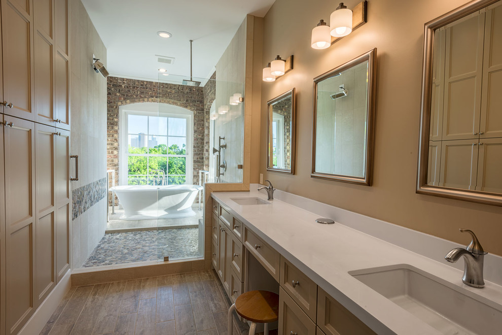 Photo of a large classic ensuite wet room bathroom in Indianapolis with recessed-panel cabinets, beige cabinets, a freestanding bath, beige tiles, multi-coloured tiles, pebble tiles, orange walls, medium hardwood flooring, a submerged sink, solid surface worktops, an open shower and white worktops.