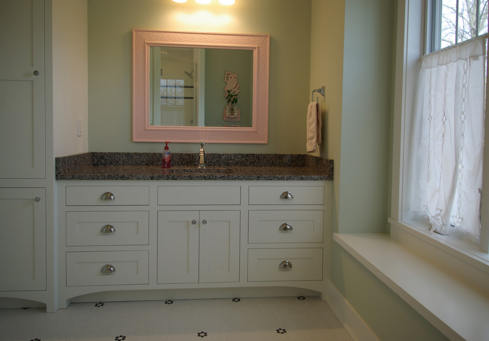 Esempio di una stanza da bagno con doccia classica di medie dimensioni con lavabo integrato, ante con riquadro incassato, ante bianche, pareti verdi, pavimento in laminato e top in granito