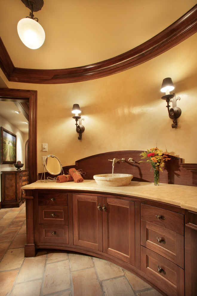 Cette image montre une salle de bain traditionnelle en bois brun avec une vasque et un placard avec porte à panneau encastré.