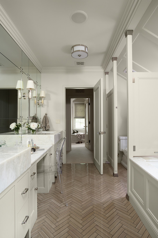 Cette photo montre une salle de bain longue et étroite chic avec des portes de placard blanches, une baignoire en alcôve et un mur blanc.