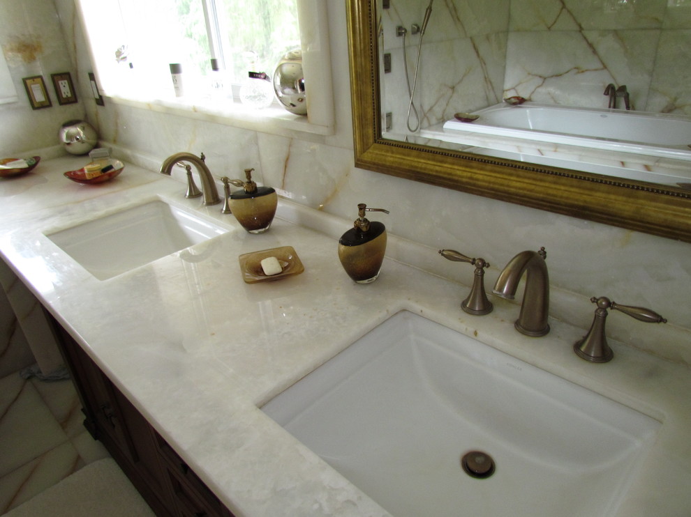 Foto di una stanza da bagno moderna con lavabo sottopiano, ante a filo, ante in legno scuro, top in onice, vasca ad alcova, doccia aperta, WC monopezzo, piastrelle bianche e lastra di pietra