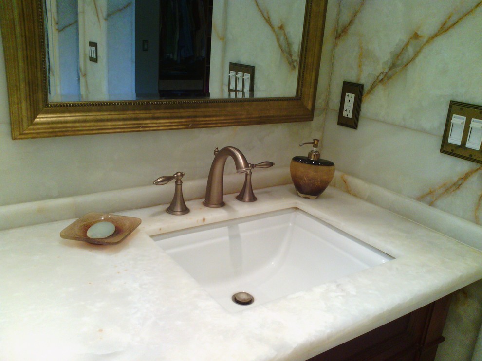 Esempio di una stanza da bagno moderna con lavabo sottopiano, ante a filo, ante in legno scuro, top in onice, vasca ad angolo, doccia aperta, WC monopezzo, piastrelle bianche e lastra di pietra