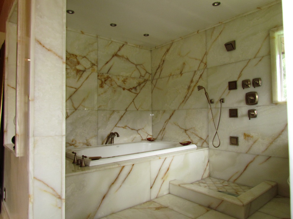 На фото: ванная комната в стиле модернизм с врезной раковиной, фасадами с декоративным кантом, фасадами цвета дерева среднего тона, ванной в нише, открытым душем, унитазом-моноблоком, белой плиткой и плиткой из листового камня