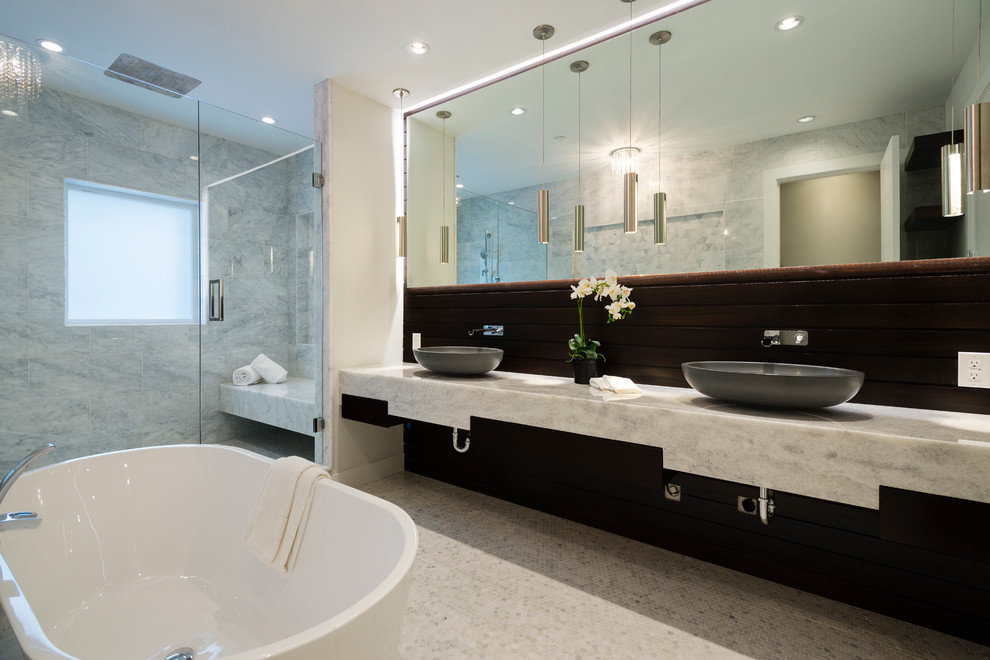 Modern inredning av ett mellanstort badrum med dusch, med släta luckor, skåp i mörkt trä, ett fristående badkar, en öppen dusch, grå kakel, kakel i småsten, grå väggar, ett undermonterad handfat, marmorbänkskiva och mosaikgolv
