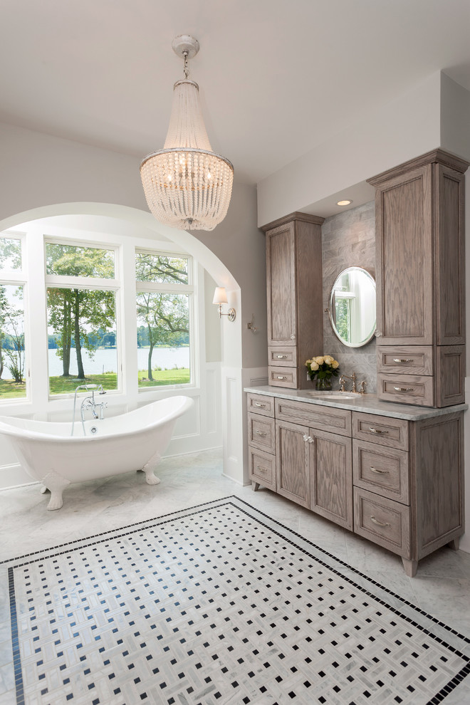 Photo of a medium sized traditional ensuite bathroom in Other with beaded cabinets, brown cabinets, a claw-foot bath, a double shower, a two-piece toilet, grey tiles, grey walls, marble flooring, a submerged sink and marble worktops.