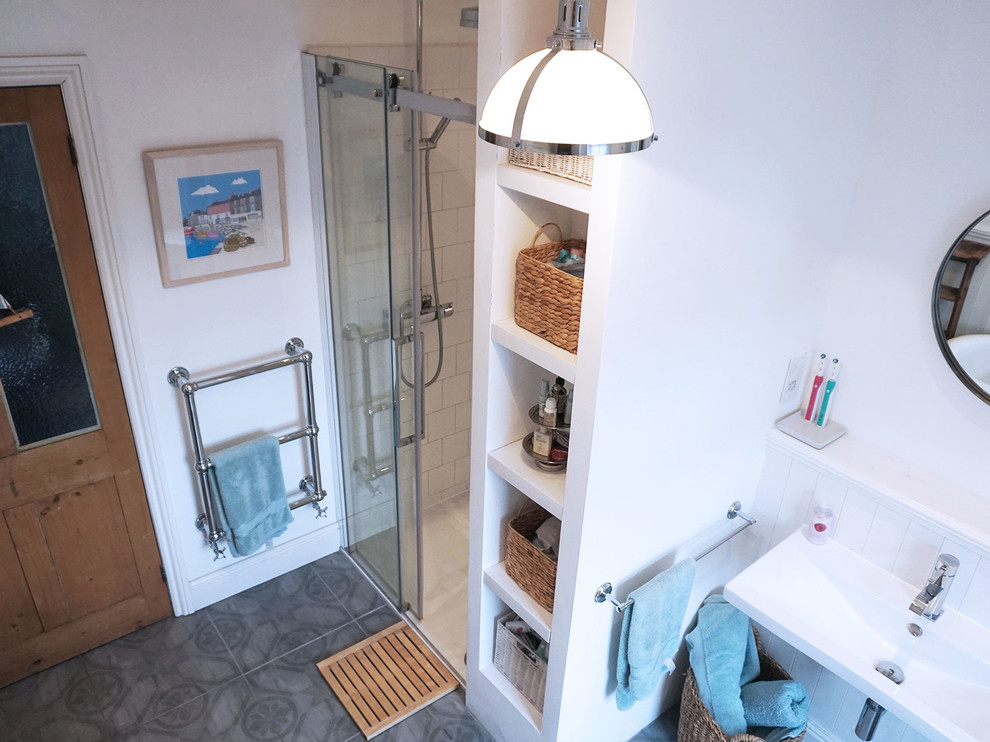Inspiration for a large beach style family bathroom in Manchester with white cabinets, a claw-foot bath, a walk-in shower, a one-piece toilet, grey tiles, porcelain tiles, white walls, porcelain flooring and a wall-mounted sink.
