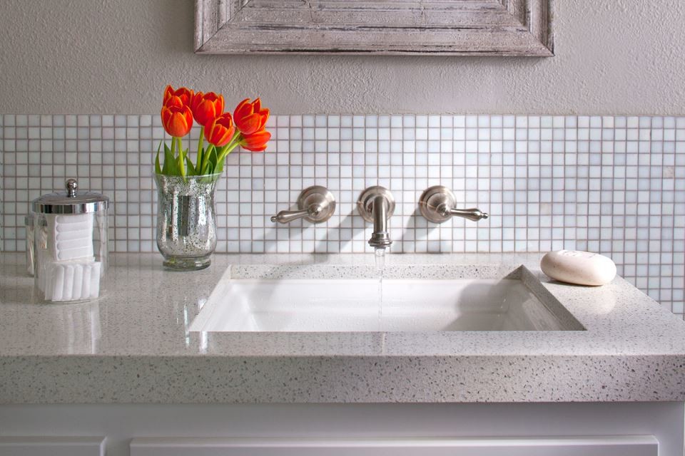 Foto på ett litet vintage badrum med dusch, med ett undermonterad handfat, släta luckor, vita skåp, bänkskiva i återvunnet glas, ett badkar i en alkov, vit kakel, glaskakel och beige väggar