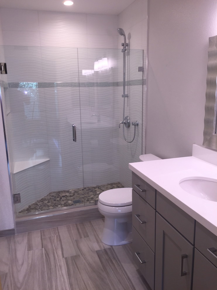 Exemple d'une salle de bain principale tendance de taille moyenne avec un placard à porte plane, des portes de placard grises, une douche double, WC séparés, un carrelage blanc, des carreaux de béton, un mur gris, un sol en carrelage de porcelaine, un plan de toilette en quartz modifié et un lavabo encastré.