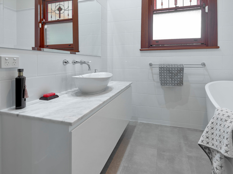 Inredning av ett klassiskt litet flerfärgad flerfärgat en-suite badrum, med släta luckor, vita skåp, ett fristående badkar, en hörndusch, vit kakel, porslinskakel, vita väggar, klinkergolv i porslin, ett fristående handfat, marmorbänkskiva, grått golv och dusch med gångjärnsdörr