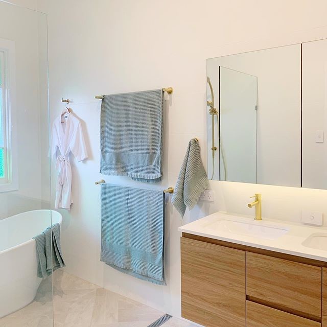 На фото: ванная комната в современном стиле с фасадами цвета дерева среднего тона, отдельно стоящей ванной, белой плиткой, белыми стенами, полом из керамической плитки, врезной раковиной, столешницей из искусственного кварца и бежевым полом