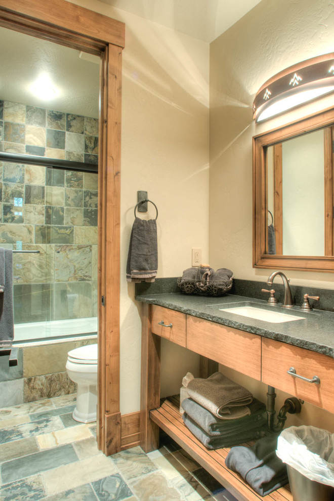 他の地域にある広いラスティックスタイルのおしゃれなマスターバスルーム (アンダーカウンター洗面器、中間色木目調キャビネット、アルコーブ型浴槽、シャワー付き浴槽	、グレーのタイル、ベージュの壁、セラミックタイルの床) の写真