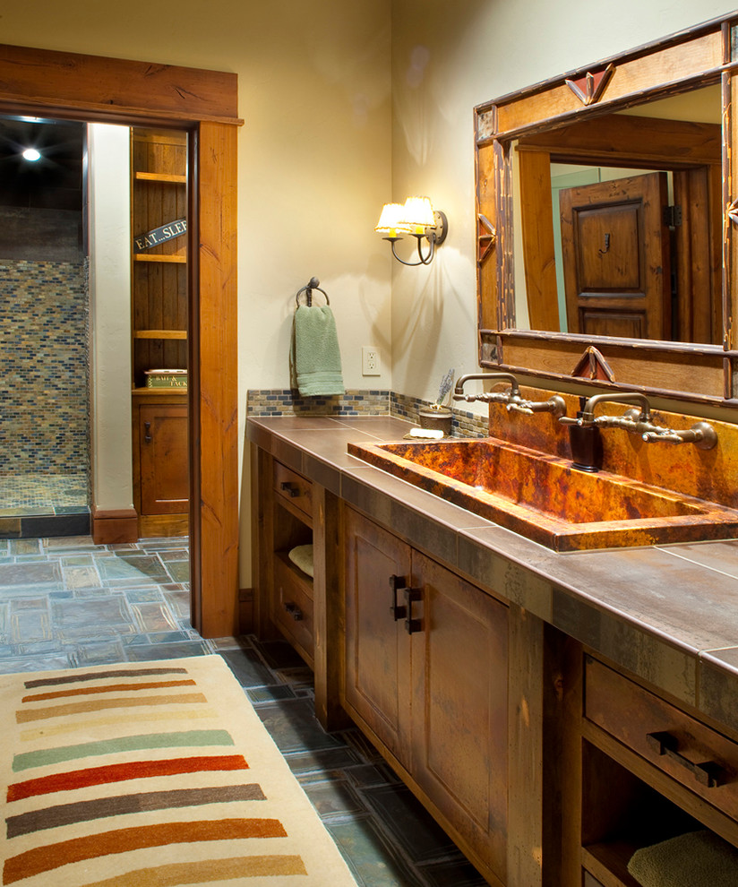 Photo of a rustic bathroom in Other with a trough sink, recessed-panel cabinets, dark wood cabinets and multi-coloured tiles.