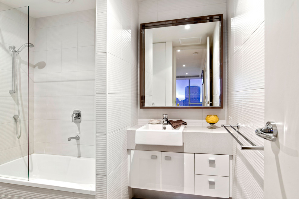 Modelo de cuarto de baño actual con armarios con paneles lisos, puertas de armario blancas, bañera empotrada, combinación de ducha y bañera, baldosas y/o azulejos blancos, lavabo sobreencimera y ducha abierta