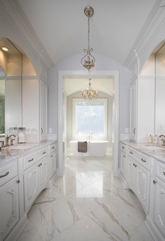 Inspiration for an expansive traditional ensuite bathroom in Houston with shaker cabinets, white cabinets, a freestanding bath, white walls, marble flooring, a submerged sink, marble worktops, white floors, a built in vanity unit and a vaulted ceiling.