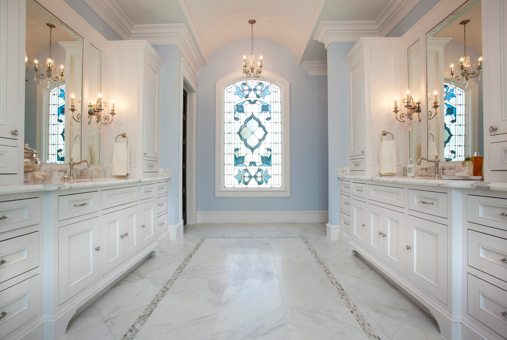 Exemple d'une grande douche en alcôve principale chic avec un placard avec porte à panneau encastré, des portes de placard blanches, une baignoire sur pieds, un carrelage blanc, un mur bleu, un sol en marbre, un plan de toilette en marbre, un sol blanc, une cabine de douche à porte battante, un plan de toilette blanc, une fenêtre et meuble double vasque.