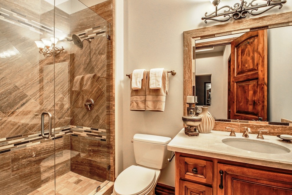 Mid-sized tuscan 3/4 beige tile and glass tile travertine floor walk-in shower photo in Phoenix with an undermount sink, raised-panel cabinets, medium tone wood cabinets, granite countertops, a one-piece toilet and beige walls