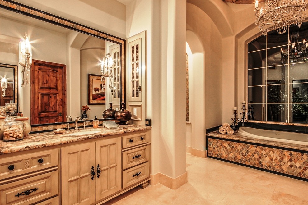 Design ideas for a large traditional ensuite bathroom in Phoenix with a submerged sink, raised-panel cabinets, light wood cabinets, a built-in bath, beige tiles, stone tiles, beige walls, travertine flooring and granite worktops.