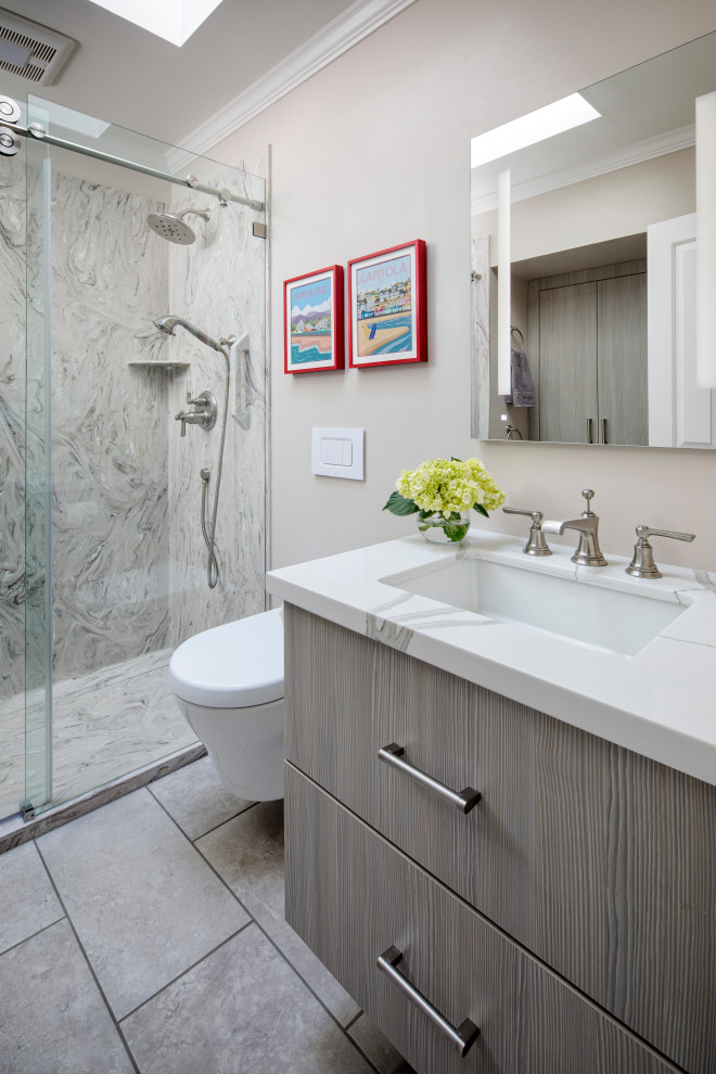 Inredning av ett modernt mellanstort vit vitt badrum, med släta luckor, grå skåp, en toalettstol med hel cisternkåpa, grå kakel, beige väggar, klinkergolv i keramik, ett undermonterad handfat, bänkskiva i kvarts, grått golv och dusch med skjutdörr