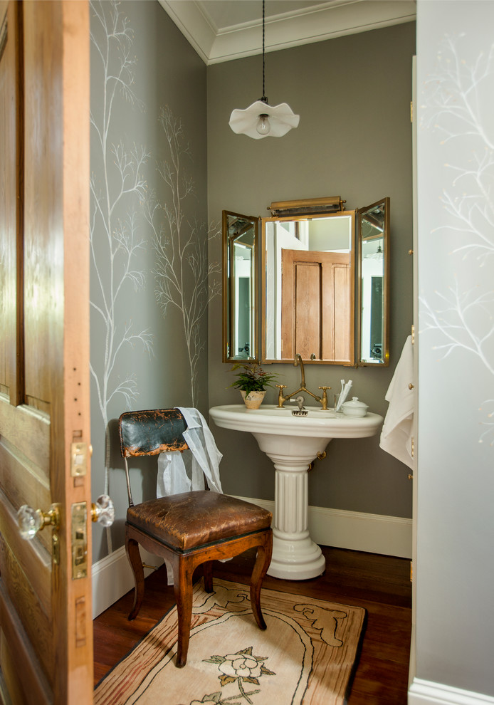 Diseño de cuarto de baño campestre con paredes grises, suelo de madera oscura, lavabo con pedestal y suelo marrón