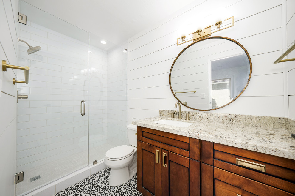 Источник вдохновения для домашнего уюта: ванная комната среднего размера в стиле рустика с фасадами в стиле шейкер, коричневыми фасадами, раздельным унитазом, белой плиткой, керамогранитной плиткой, белыми стенами, полом из керамогранита, врезной раковиной, столешницей из гранита, разноцветным полом, душем с распашными дверями, разноцветной столешницей, тумбой под одну раковину, встроенной тумбой и стенами из вагонки