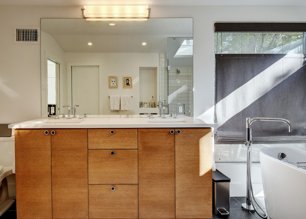 This is an example of a large contemporary ensuite bathroom in Austin with a submerged sink, flat-panel cabinets, medium wood cabinets, engineered stone worktops, a freestanding bath, a walk-in shower, a one-piece toilet, black and white tiles, white walls, ceramic flooring, ceramic tiles, black floors and a hinged door.