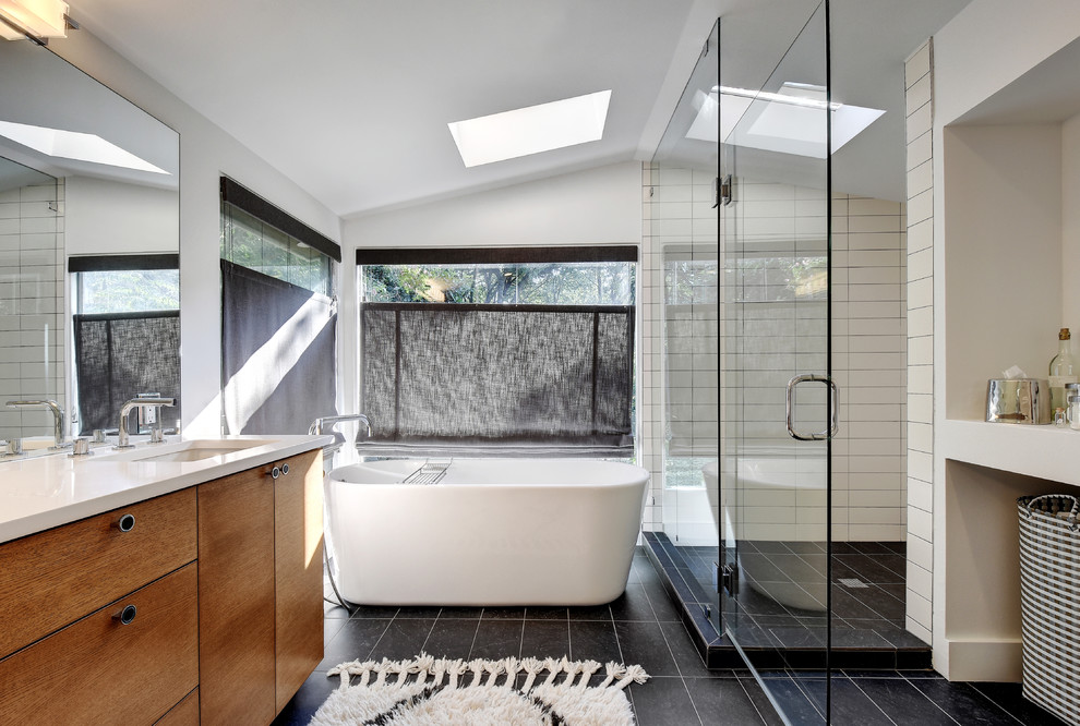 Design ideas for a medium sized contemporary ensuite bathroom in Austin with a submerged sink, flat-panel cabinets, medium wood cabinets, engineered stone worktops, a freestanding bath, a walk-in shower, a one-piece toilet, black and white tiles, cement tiles, white walls, ceramic flooring, black floors and a hinged door.