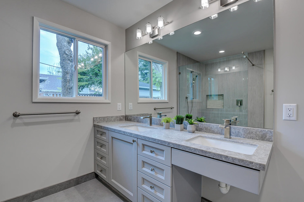 Example of a large trendy master gray tile and ceramic tile ceramic tile and gray floor walk-in shower design in San Francisco with recessed-panel cabinets, gray cabinets, a one-piece toilet, gray walls, a drop-in sink, quartzite countertops, a hinged shower door and gray countertops
