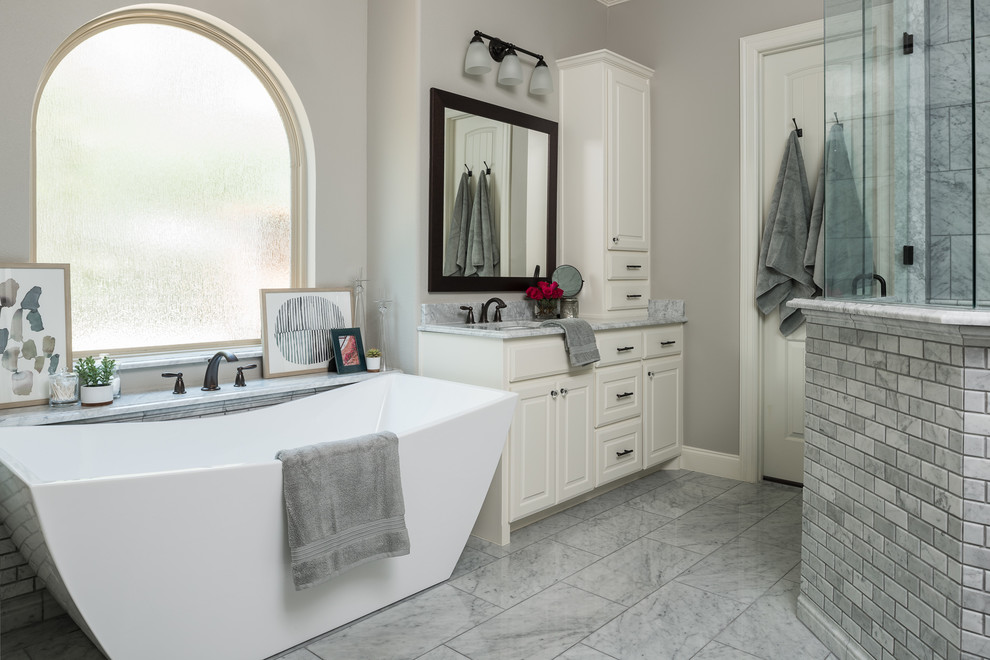 Large country master gray tile marble floor and gray floor bathroom photo in Dallas with recessed-panel cabinets, white cabinets, a one-piece toilet, gray walls, an undermount sink, marble countertops, a hinged shower door and gray countertops