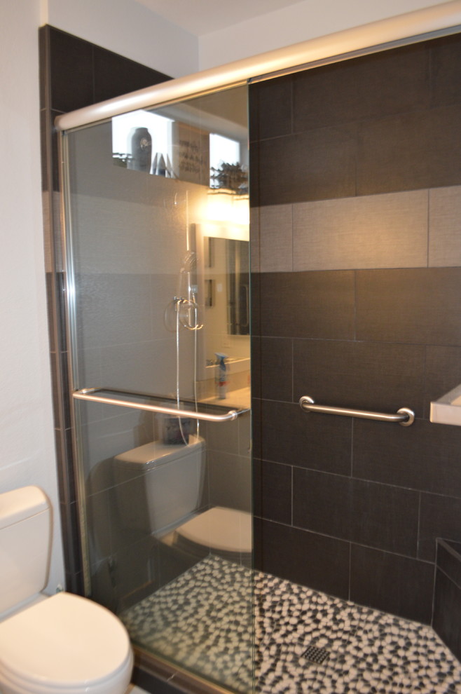 Exempel på ett modernt flerfärgad flerfärgat badrum, med skåp i shakerstil, vita skåp, en dusch i en alkov, en toalettstol med separat cisternkåpa, svart kakel, kakel i småsten, grå väggar, klinkergolv i porslin, ett undermonterad handfat, bänkskiva i kvarts, grått golv och dusch med skjutdörr