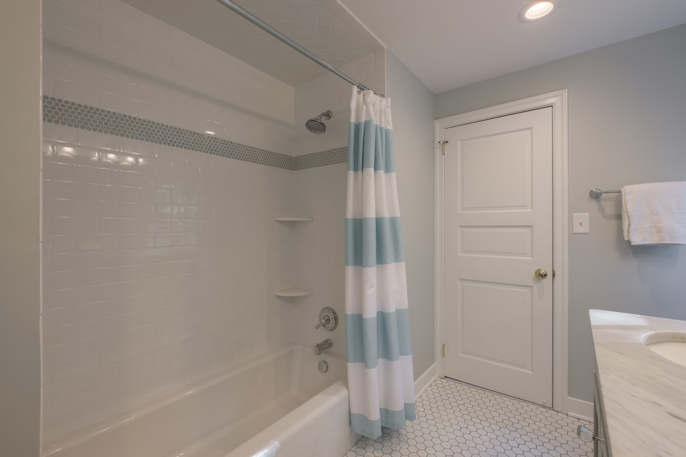 На фото: детская ванная комната среднего размера в современном стиле с плоскими фасадами, белыми фасадами, душем над ванной, белой плиткой, керамической плиткой, серыми стенами, полом из керамической плитки, врезной раковиной и мраморной столешницей с