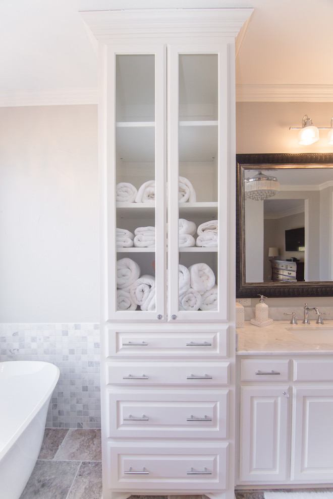 Источник вдохновения для домашнего уюта: большая главная ванная комната в современном стиле с белыми фасадами, отдельно стоящей ванной, двойным душем, раздельным унитазом, серыми стенами, полом из травертина, врезной раковиной, мраморной столешницей, серым полом, душем с распашными дверями, белой столешницей, стеклянными фасадами, белой плиткой и каменной плиткой