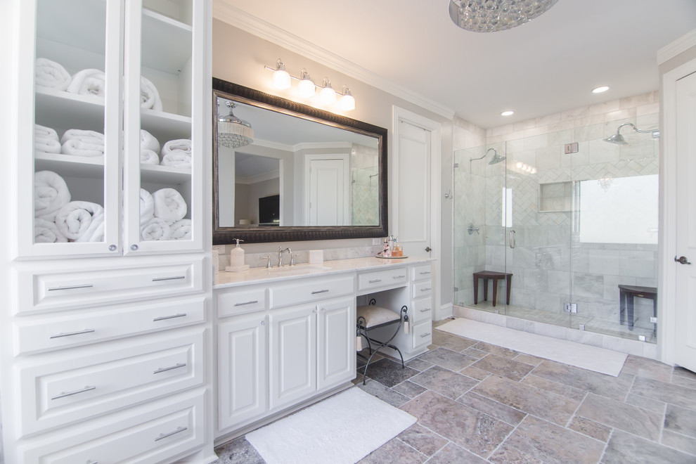 Пример оригинального дизайна: большая главная ванная комната в современном стиле с белыми фасадами, отдельно стоящей ванной, двойным душем, раздельным унитазом, серыми стенами, полом из травертина, врезной раковиной, мраморной столешницей, серым полом, душем с распашными дверями, белой столешницей, стеклянными фасадами, белой плиткой и каменной плиткой